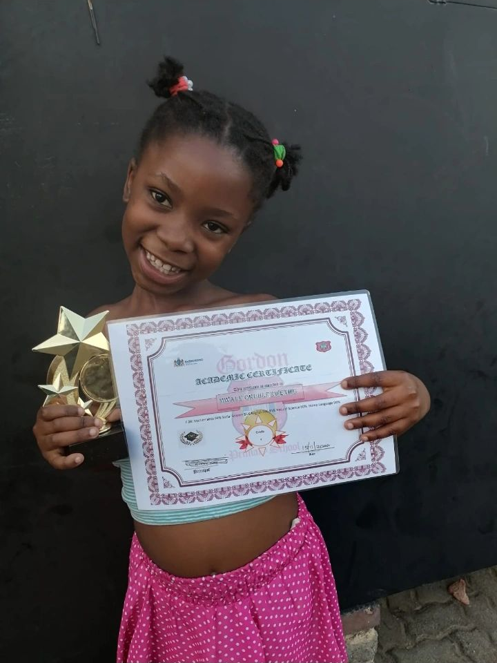 Scholar proudly holding a Gordon Academic Certificate and gold star trophy